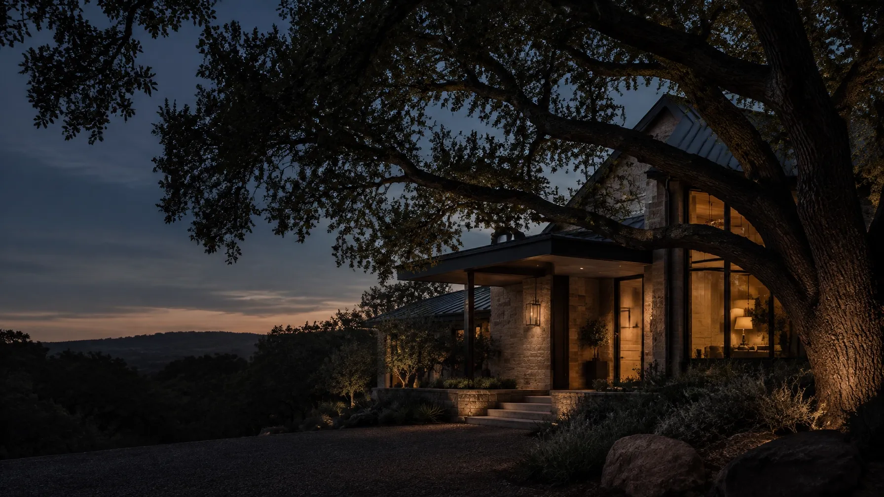 A North Texas home at blue hour behind mature oak branches